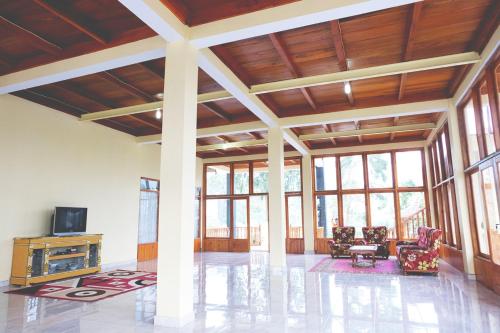 a large living room with windows and a tv at Villa Cempaka Pangalengan in Cibeureum