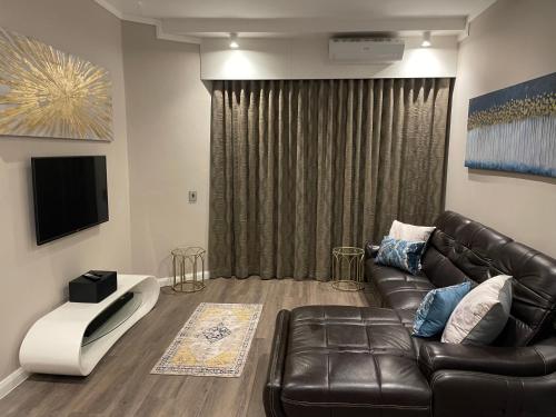 a living room with a leather couch and a television at Stazamaine 1421 in Pretoria