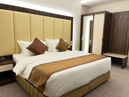 a bedroom with a large bed with a wooden headboard at فندق النزيل الذهبي - Golden Guest Hotel in Jazan