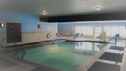 a large swimming pool with blue chairs in a building at Holiday Inn Express & Suites Indianapolis North - Carmel by IHG in Carmel