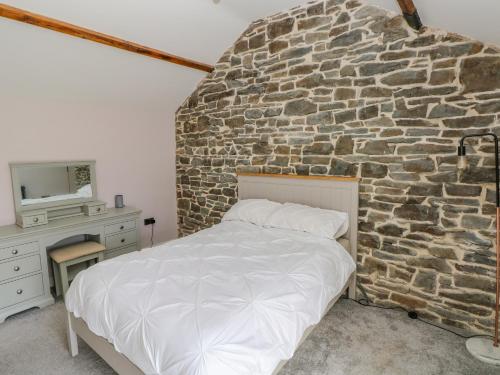 a bed in a room with a stone wall at Y Bwythyn Bach in Burry Port
