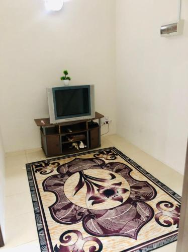 a living room with a television and a rug at Homestay Cahaya 1 Seri Iskandar in Seri Iskandar