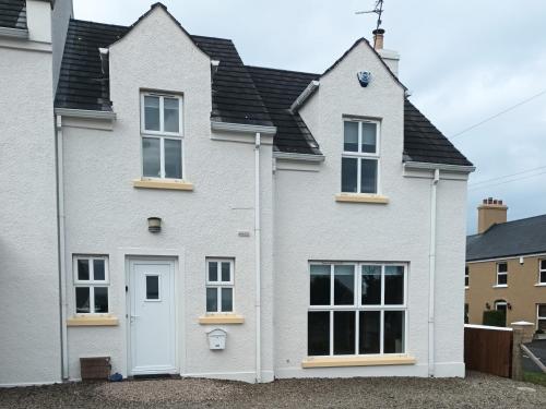 a white house with a black roof at Stillwaters in Bushmills