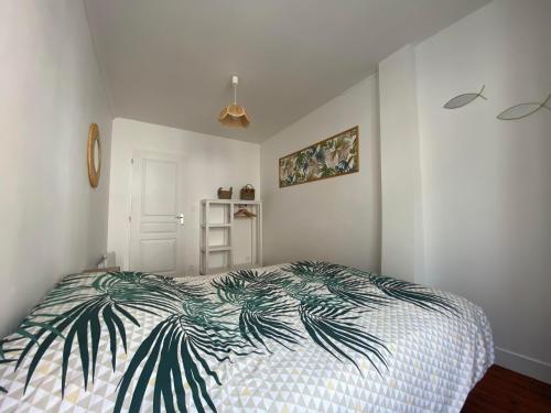 a bedroom with a bed with a palm leaf bedspread at L'Abri-gîte - Appartement moderne idéalement situé en centre ville in Dieppe
