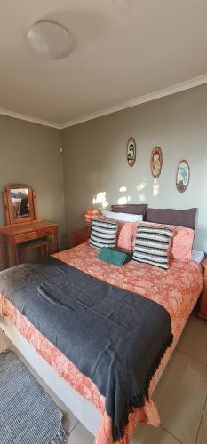 a bedroom with a large bed with pillows on it at Cosy Cottage in Port Shepstone