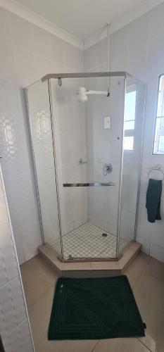 a shower stall in a bathroom with a green mat at Cosy Cottage in Port Shepstone