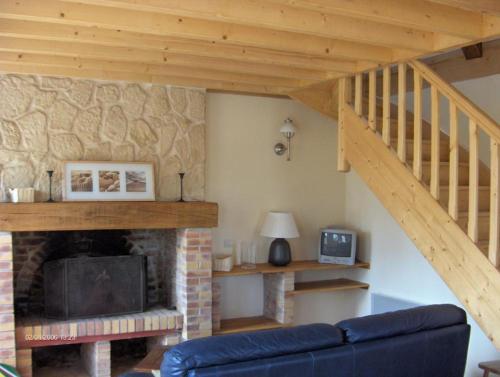 sala de estar con chimenea y escalera de madera en Gîte de la Ferme Dufresne en Bernières