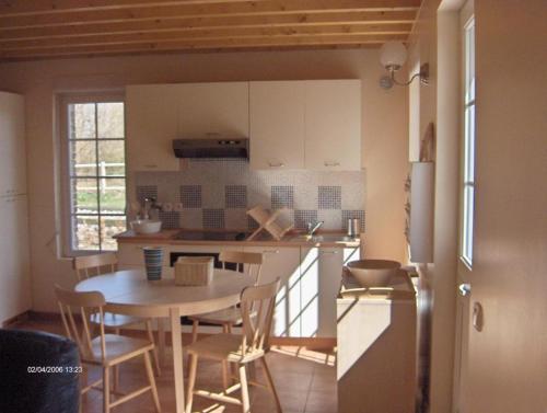 uma cozinha e sala de jantar com mesa e cadeiras em Gîte de la Ferme Dufresne em Bernières
