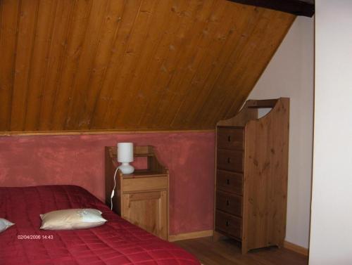 Gîte de la Ferme Dufresne في Bernières: غرفة نوم بسرير احمر وسقف خشبي