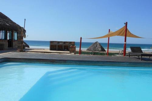 una piscina accanto a una spiaggia con tenda di Casa Coco Palmeira a Inhambane