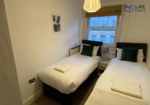 two beds in a small room with a window at Luke Stays - Clayton Street in Newcastle upon Tyne