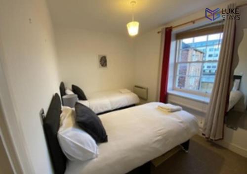 a hotel room with two beds and a window at Luke Stays - Clayton Street in Newcastle upon Tyne