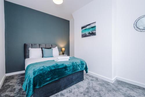 a bedroom with a bed with a blue accent wall at Cosy 3 bed 3 bath house - Central Liverpool -Self Check-In & Free Parking! in Liverpool