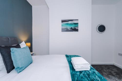 a white bedroom with a white bed with blue pillows at Cosy 3 bed 3 bath house - Central Liverpool -Self Check-In & Free Parking! in Liverpool