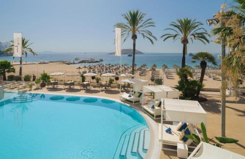 a pool with chairs and palm trees and the ocean at Sol House The Studio - Calviá Beach - Adults Only in Magaluf
