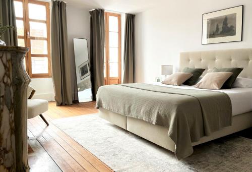 biała sypialnia z dużym łóżkiem i oknami w obiekcie La Place B&B w mieście Sancerre