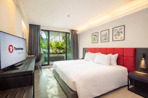 a hotel room with a large bed and a flat screen tv at Travelodge Phuket Town in Phuket Town