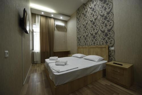 a bedroom with a bed with white sheets and a mirror at Family Hotel Avlabar in Tbilisi City