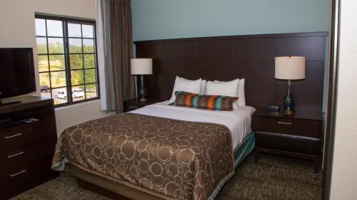 コロラドスプリングスにあるStaybridge Suites Colorado Springs North, an IHG Hotelのベッドとテレビが備わるホテルルームです。