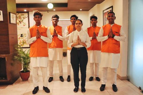 a group of people in orange and white tying their ties at Hotel Clarks Collection Bhavnagar in Bhavnagar