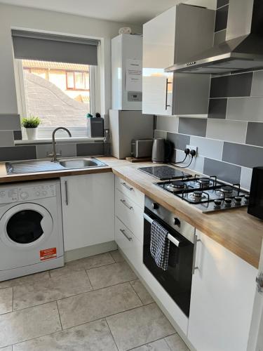 a kitchen with a stove and a washing machine at City Beach AirBnB Southend on Sea, in Southend-on-Sea