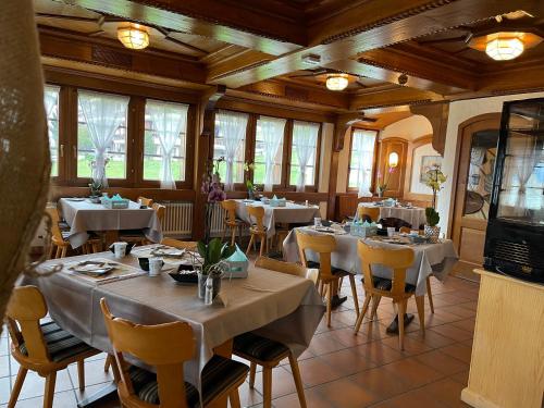 ein Restaurant mit weißen Tischen, Stühlen und Fenstern in der Unterkunft Hotel Restaurant Rothorn in Visperterminen