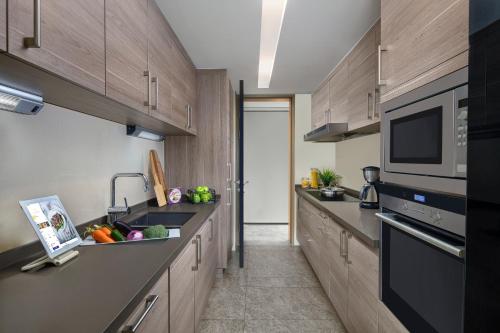 a kitchen with wooden cabinets and a sink and a microwave at Ascott IFC Guangzhou - Free Shuttle Bus For Canton Fair in Guangzhou