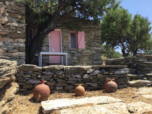 ein Steinhaus mit drei Vasen vor einer Wand in der Unterkunft OWL’S NEST/THE PINK COTTAGE in Ioulis