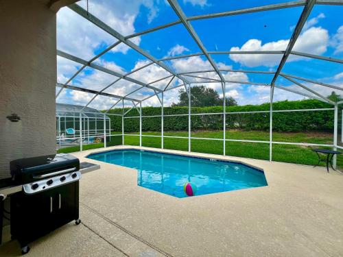 uma piscina com um telhado de vidro e um grelhador em Grand Family Superior 4BR House near Disney Parks em Davenport