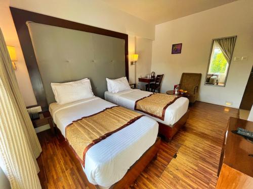 a hotel room with two beds and a desk at Hotel Clarks Collection Bhavnagar in Bhavnagar