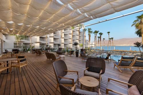 a deck with chairs and tables and a view of the ocean at Aria in Eilat