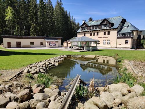 a large house with a pond in front of it at Penzion Bílá voda in Harrachov