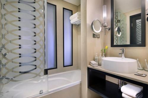 a bathroom with a sink and a tub and a shower at Voco - Riyadh by IHG in Riyadh