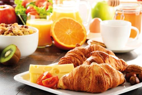 a plate of food with croissants and other breakfast foods at IntercityHotel Berlin Airport Area North in Schönefeld