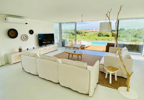 uma sala de estar com um sofá branco e uma televisão em Villa Possanco, Comporta beach villa em Comporta