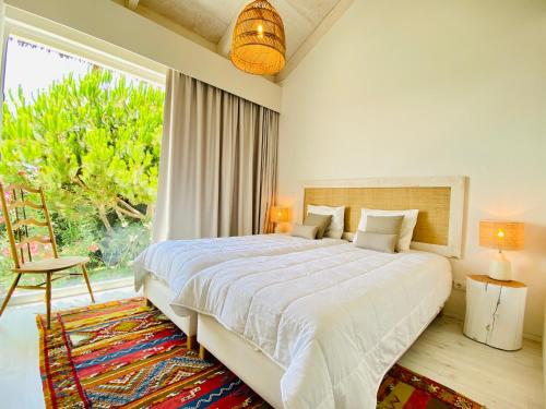 - une chambre avec un grand lit et une grande fenêtre dans l'établissement Villa Possanco, Comporta beach villa, à Comporta
