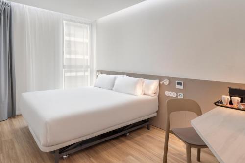 B&B HOTEL Santo Tirso في سانتو تيرسو: سرير أبيض في غرفة مع طاولة وكرسي