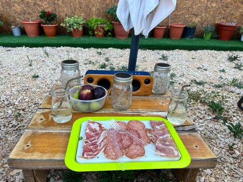 une table avec une assiette de viande et un bol de fruits dans l'établissement La casetta sotto l'albero LA CAROVANA GITANA, à Vasto