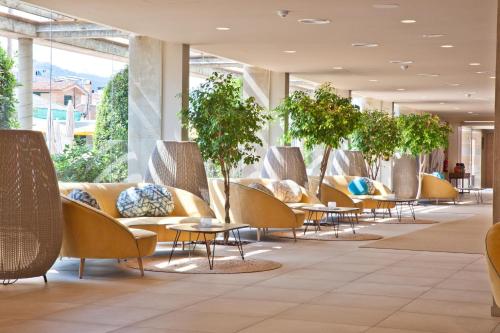 un vestíbulo con mesas, sillas y macetas en 30º Hotels - Hotel Pineda Splash, en Pineda de Mar