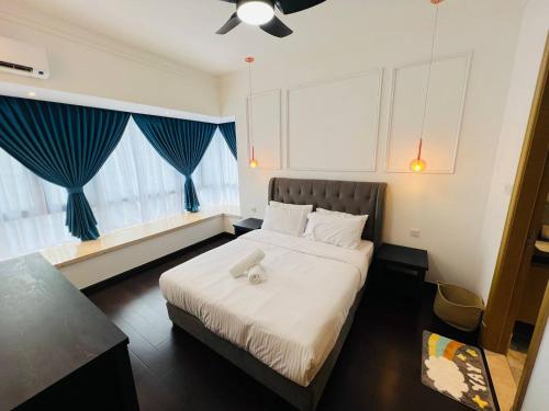 a bedroom with a large bed with blue curtains at R&F PRINCESS COVE at ANJU in Johor Bahru