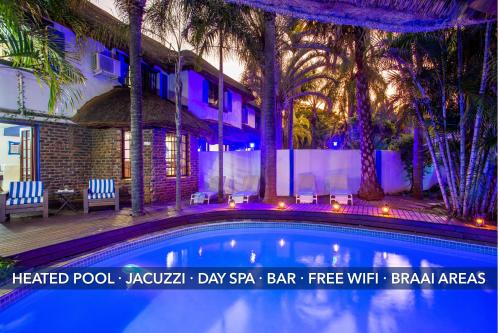 uma grande piscina em frente a uma casa com palmeiras em The Villa Manor & Spa em Bela-Bela