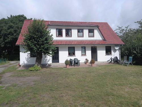 a white house with a red roof and a yard at Ruegen_Fewo 155 in Veikvitz