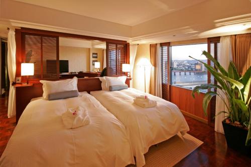 a bedroom with a large white bed with a large window at Miyazaki Kanko Hotel in Miyazaki