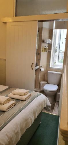 1 dormitorio con cama, aseo y ventana en CORBIERE GUEST HOUSE, en Weston-super-Mare