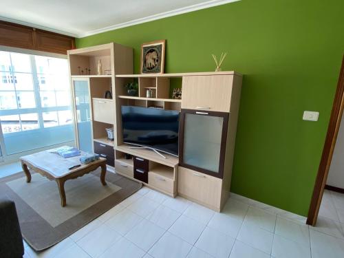 uma sala de estar com uma parede verde e uma televisão em Gamboa em Vigo