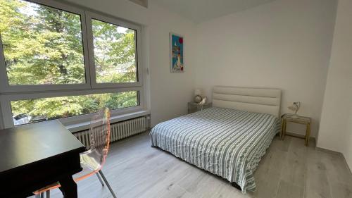 1 dormitorio con 1 cama, escritorio y 2 ventanas en La casa sul lago, en Maroggia