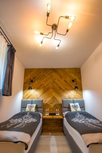 two beds in a room with a wooden wall at Apartament Muszyna in Muszyna