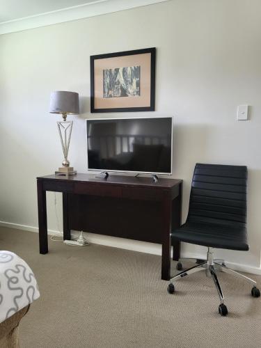 a desk with a television and a chair in a room at Blue on Cooper in Katoomba