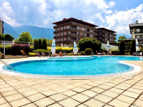 a swimming pool in a resort with chairs and umbrellas at Pirin Dream View Apartments in Razlog