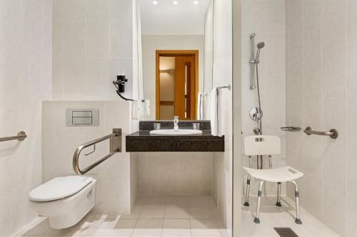 a white bathroom with a toilet and a sink at Ramada by Wyndham Madrid Tres Cantos in Tres Cantos